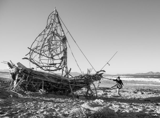Young woman on decorative wooden ship near water on shore