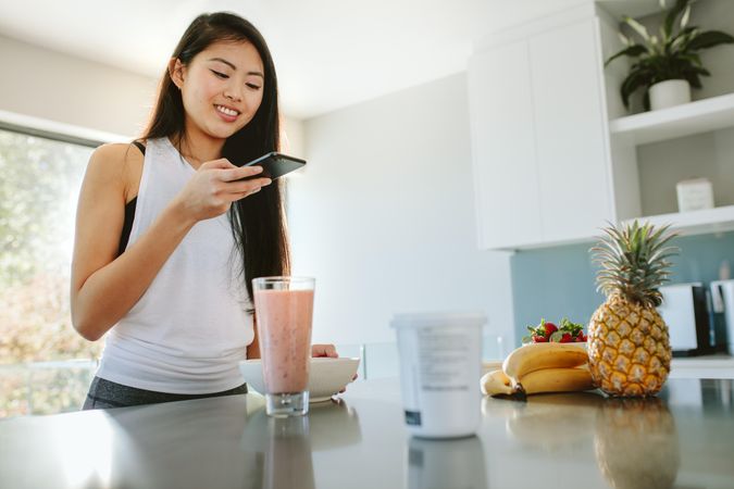 Young woman taking photos of a healthy breakfast using a mobile phone