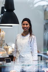 Cheerful woman standing at counter in bakery