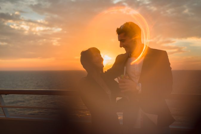 Young people kissing in sunset light on ship