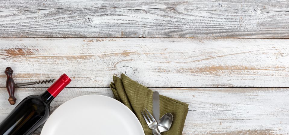 Top view of clean dinner plate setting with red wine on rustic table