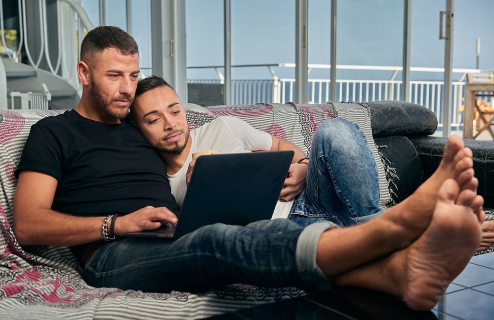 Happy gay couple using laptop at home