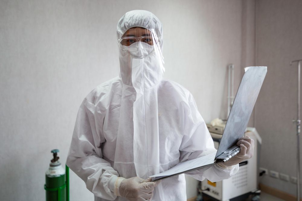 Portrait of doctor in PPE suit holding patient clipboard at emergency room in hospital