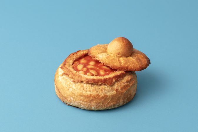 Baked beans in a bread bowl isolated on a blue background