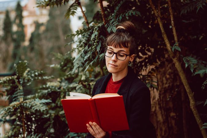 Young woman reading book on bench in park