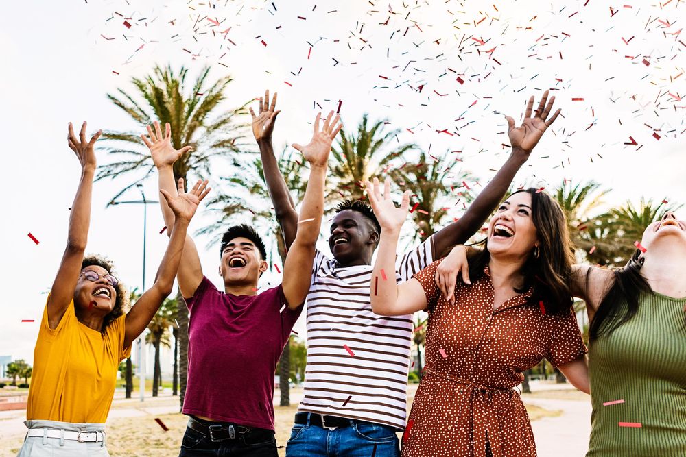 Multi-racial people throwing confetti and enjoying a summer party together