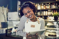 Woman with tablet and cell phone to ear taking reservation in a cafe