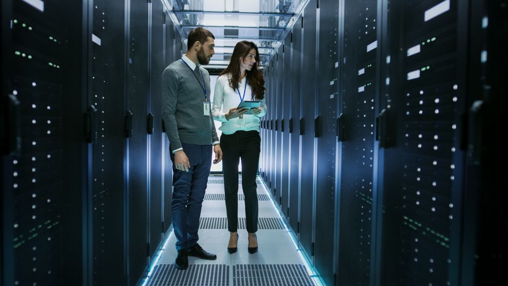 Female and Male IT Engineers Discussing Technical Details in a Working Data Center