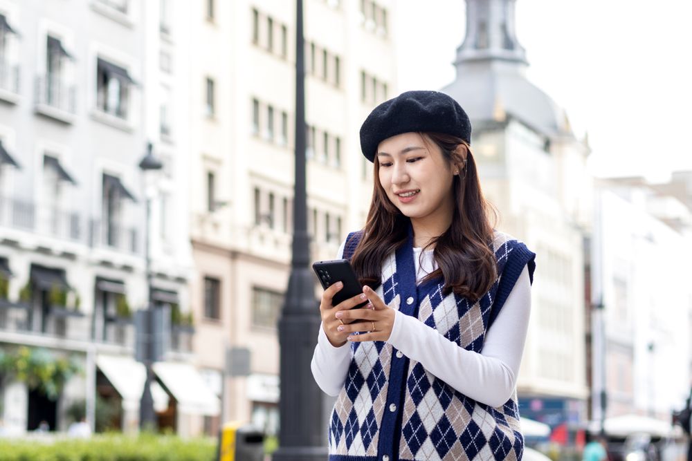Young Asian Woman Walking and Using Smartphone in the City