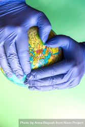 Hands in blue latex gloves holding globe, with copy space 0yXlqO