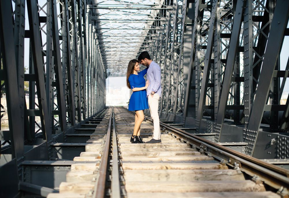 Amorous couple bonding on railway under bridge