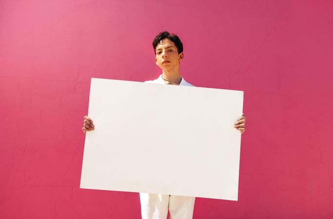 Confident man holding a blank placard against a pink background