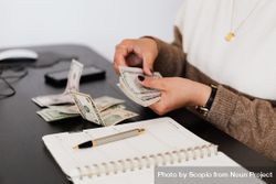Cropped image of woman counting five dollar bills sitting in an office 5wKYL5