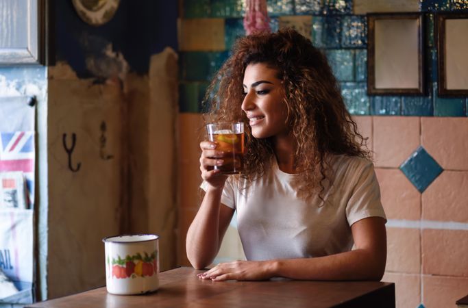 Arab woman in casual clothes drinking a soda at restaurant table