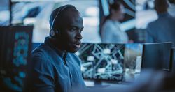 Black Man Effectively Multitasking with Supporting Clients on a Phone Call and Computer Work