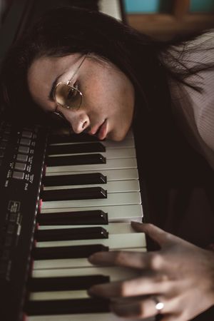 young woman with her head resting on the piano