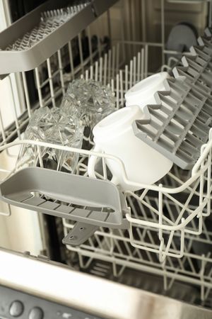 Modern open dishwasher with clean cups and glasses