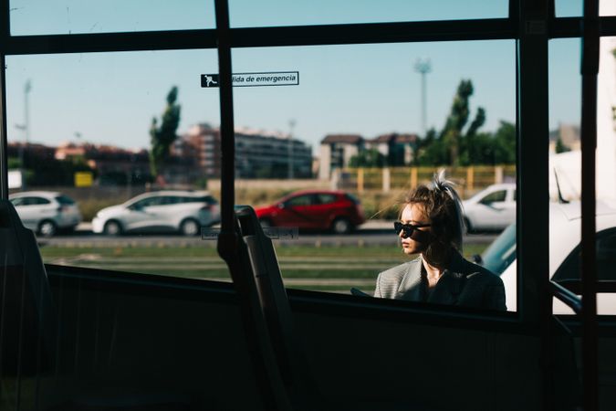 Trendy businesswoman and sunglasses leaning behind bus