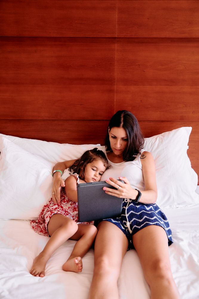 Little girl and her mother using a tablet in a hotel room