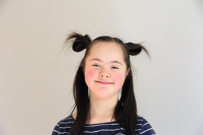 Beautiful young child with Down syndrome looking at camera and smiling
