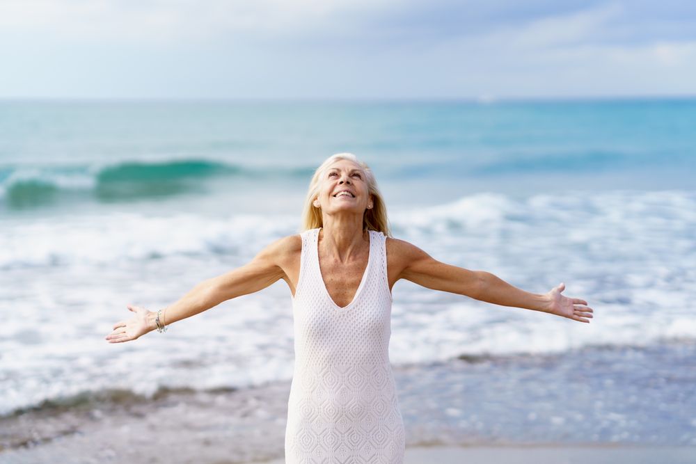 Mature woman opening her arms on a tropical beach