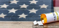 Open prescription bottle of opioid pain killer tablets on USA rustic flag 43Dwrb