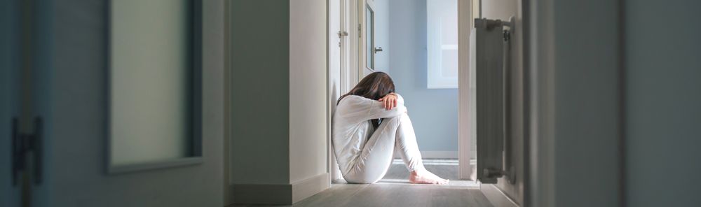 Woman in pajamas sitting on the floor of a mental health center