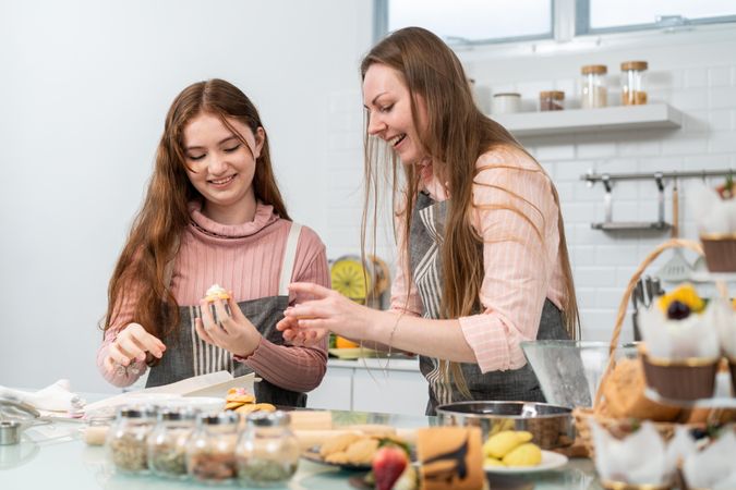 Mother and daughter enjoying cupcakes in kitchen