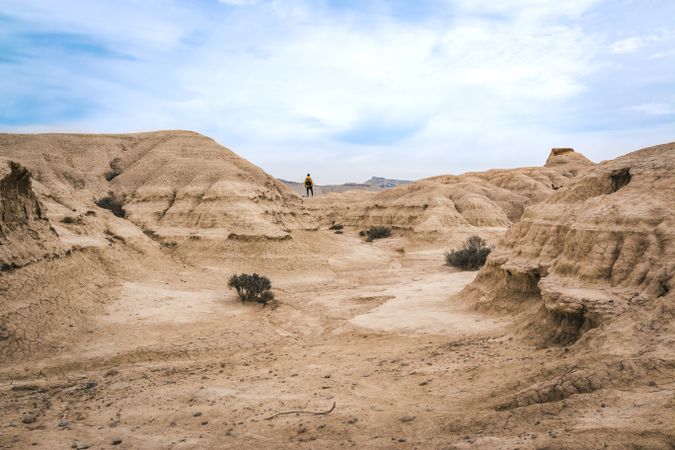 Man walking on amazing landscape of desert hills on background of blue sky