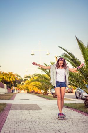 Young girl riding in a skateboard outdoors on summer