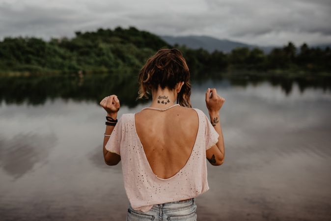 Anonymous female standing towards sea on sunset