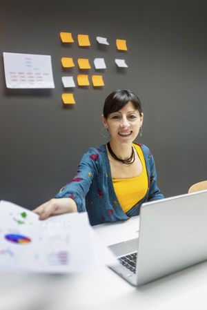 Smiling businesswoman giving documents to camera