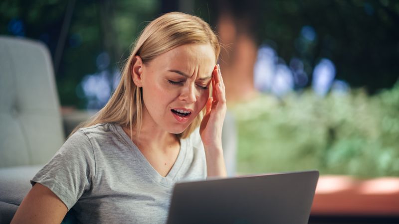 Human Going Through Headache: Close Up of a Female Working on Laptop Computer and Experiencing Discomfort and Migraine.