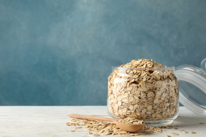 Glass jar with oatmeal and spoon on wooden table