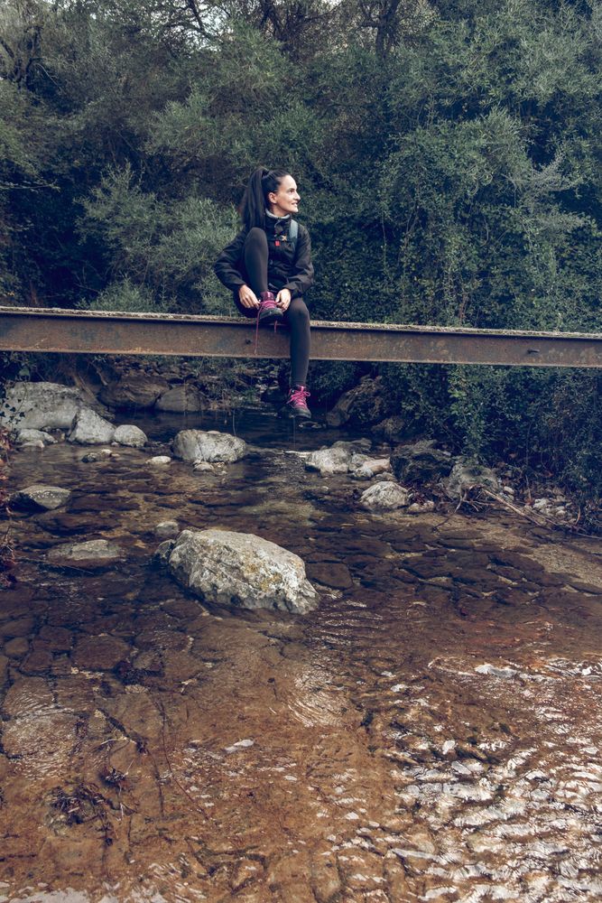 Traveler sitting on bridge above brook in woods