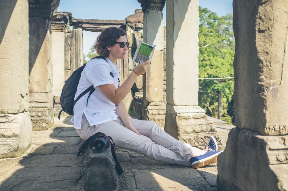 Female tourist reading guidebook in ruins
