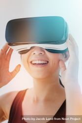 Close up shot of smiling young woman using the virtual reality headset against grey background bGoAYb
