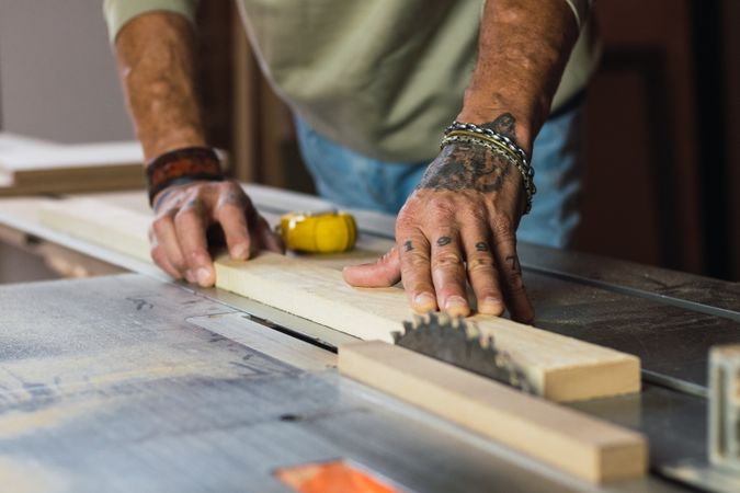 Crop male carpenter cutting wood with circular saw
