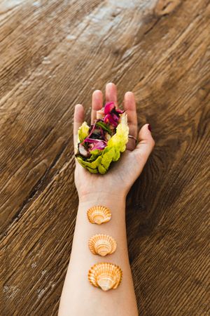 Crop female hand with lettuce wrap and seashells