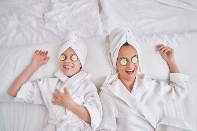 Cheerful mother and boy with cucumber eye masks