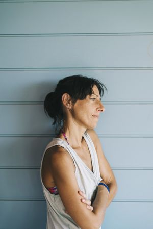 Portrait of hispanic woman with summer dress and ponytail while leaning on wood wall