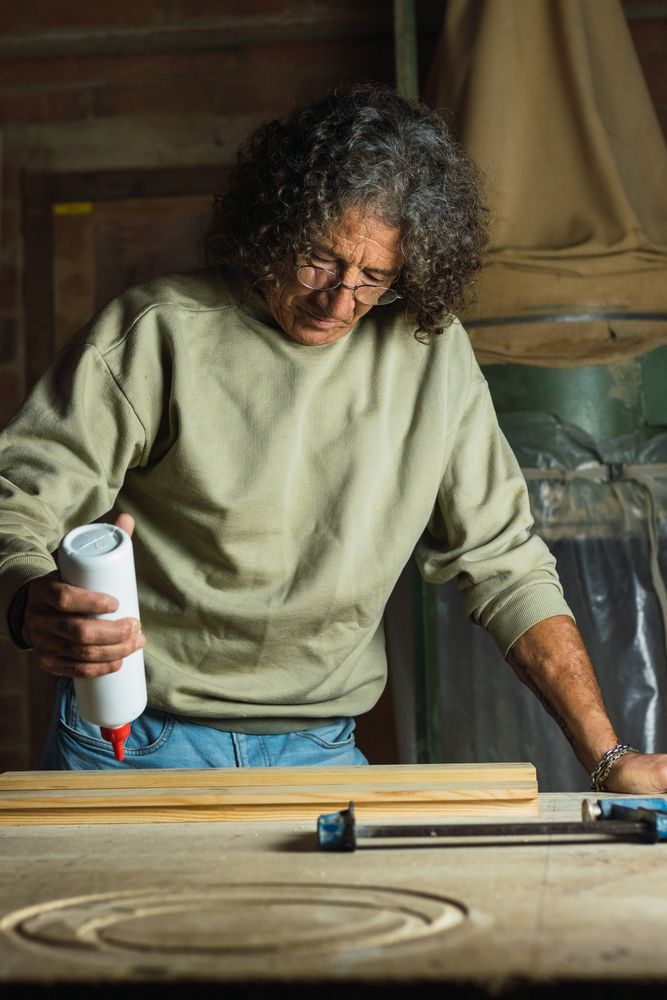 Carpenter gluing wooden board in workshop