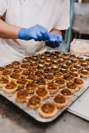 Crop cook decorating pastry with nuts