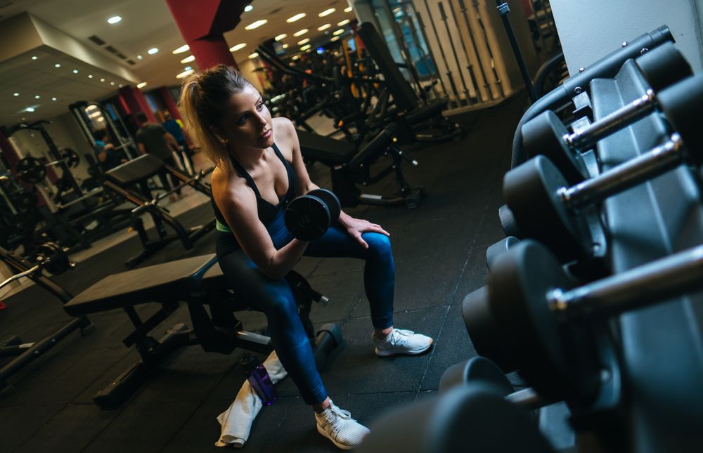 Woman lifting dumbbells on bench