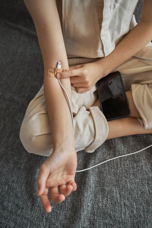 Faceless kid attaching charging wire to arm