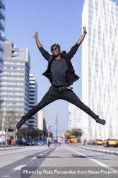 Black man wearing casual clothes jumping against city background 5lVRaN