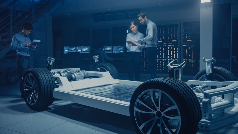 Diverse Automobile Engineers Talking while Working on Electric Car Platform Chassis Prototype
