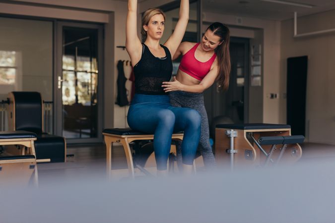 Women doing pilates exercises sitting on bench with raised hands