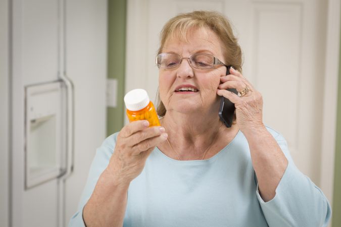 Older Woman on Cell Phone Holding Prescription Bottle