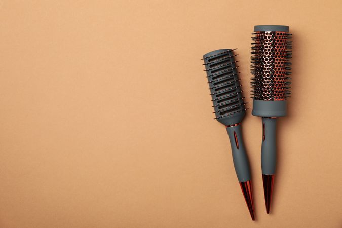 Hair brushes on brown background, space for text